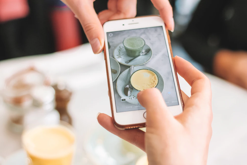 Persona fotografiando con el móvil un café para publicarlo en redes sociales
