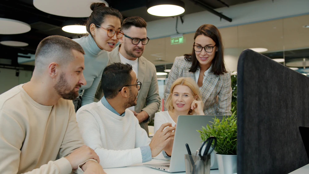 Equipo de marketing revisando una estrategia digital alrededor de un portátil