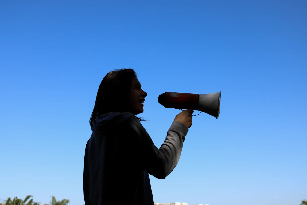Silueta de una mujer hablando con un megáfono