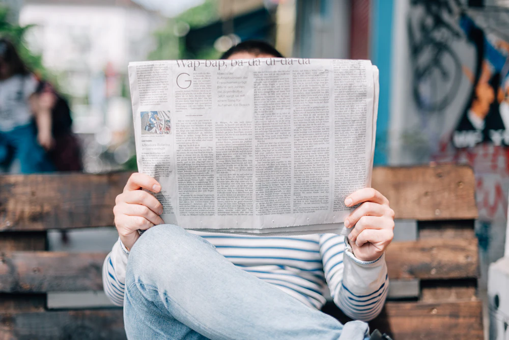 Persona leyendo el periódico sentada en un banco
