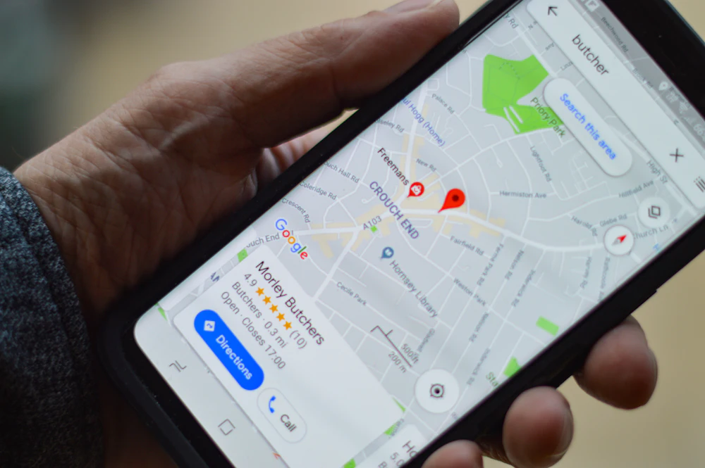 Mano sosteniendo un móvil con Google Maps abierto buscando negocios cercanos